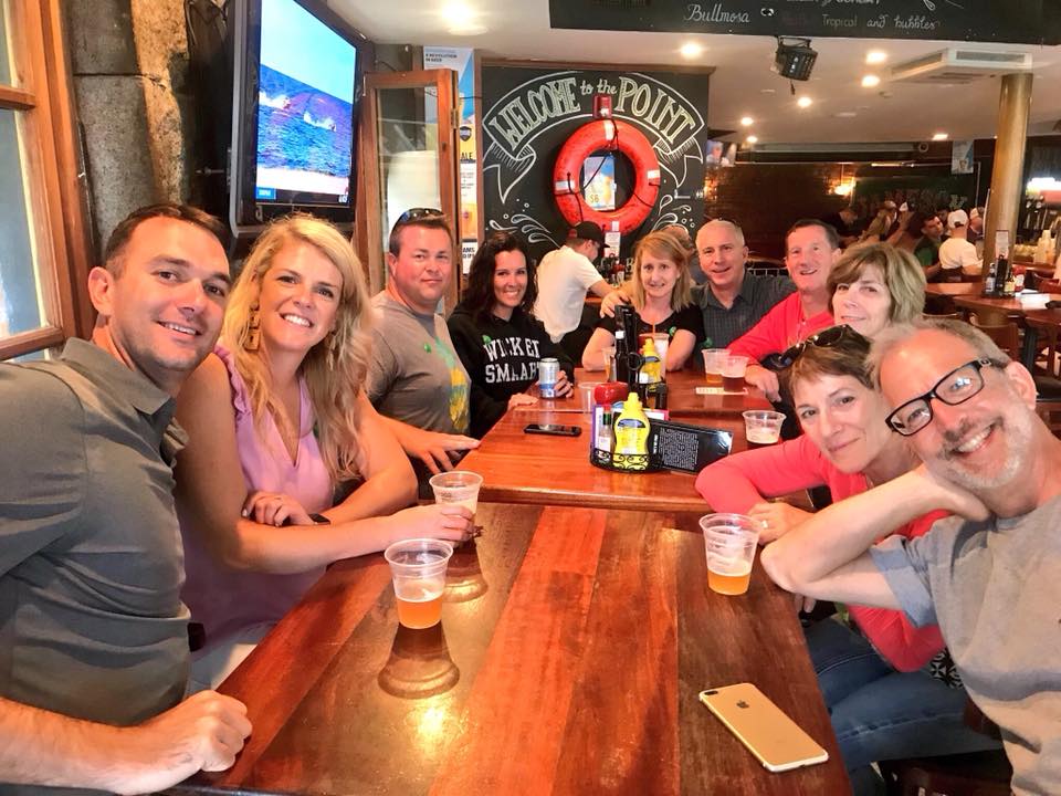 Corpotate – Team Outing Pub Crawl – Thumbnail Image a group of people sitting at a table posing for the camera