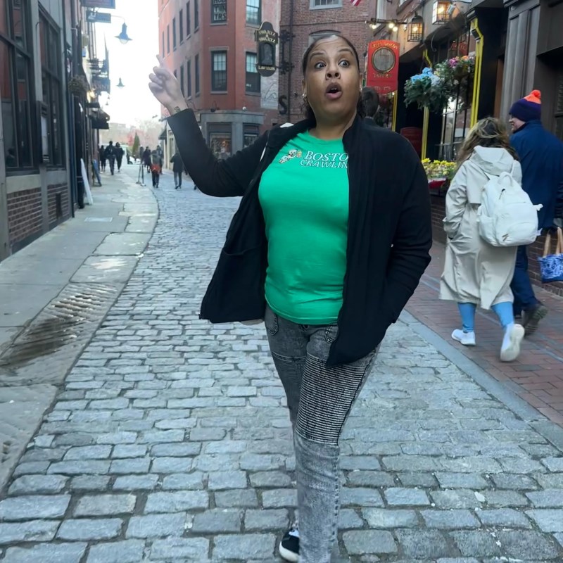 C_Hull a person walking down a street next to a brick building